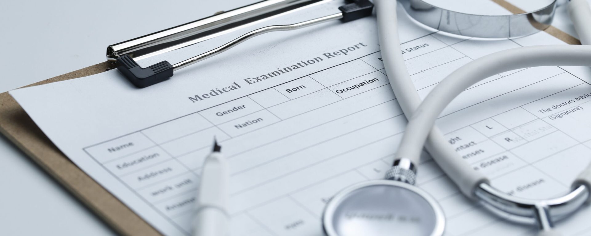 Medical examination report and stethoscope on white desktop